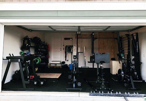 Garage gym with cardio machines, weight storage, lifting platform, and functional training setup.