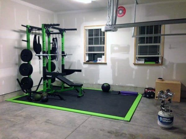 Garage gym with green-accented weight rack, concrete flooring, and compact workout setup.