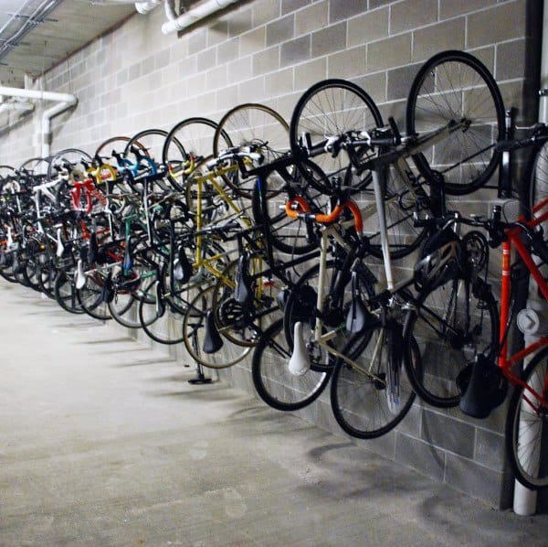 Row of bicycles hanging vertically on industrial-style wall racks in a garage storage area.