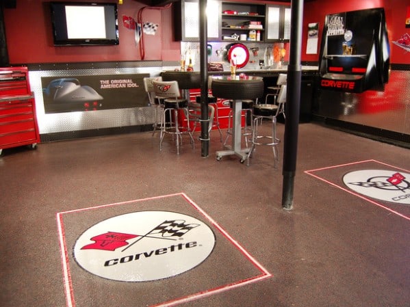 Garage-themed man cave with Corvette logos, sleek bar stools, and a red tool chest for a bold and automotive-inspired design