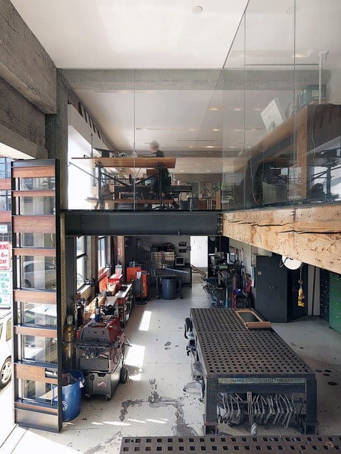 Industrial-style workspace with a garage vibe, glass mezzanine, metal furniture, and street-facing windows