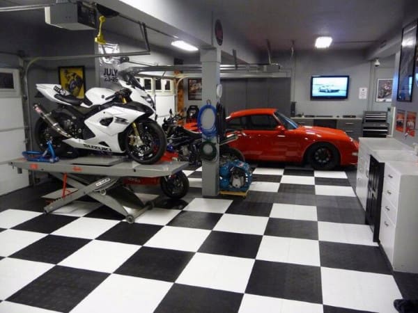 Garage with a white motorcycle on a lift and a sleek red sports car on a checkered floor