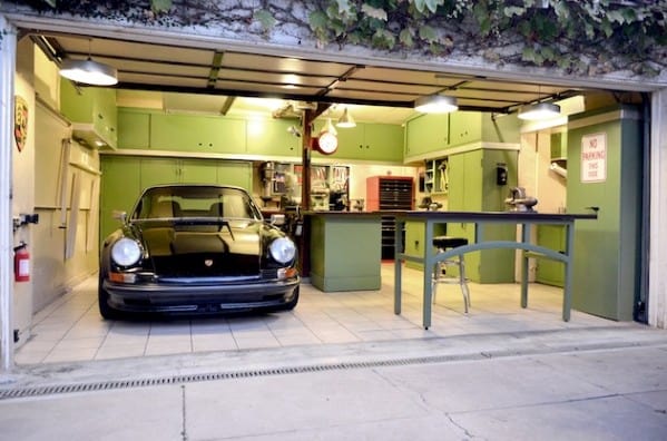 Classic car garage man cave with green cabinets, a black vintage Porsche, and a functional workbench setup for enthusiasts