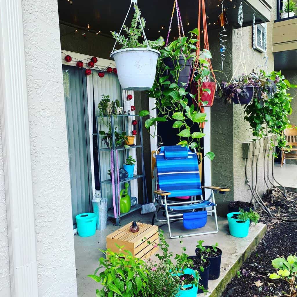 Small garden patio with hanging plants, a colorful chair, potted plants, and string lights.