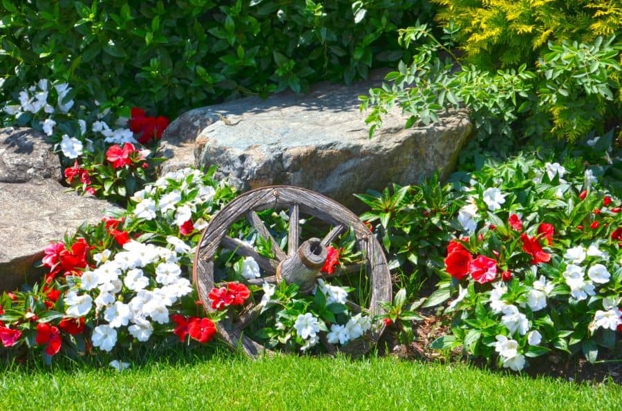 carriage wheel garden feature white and red flowers stone