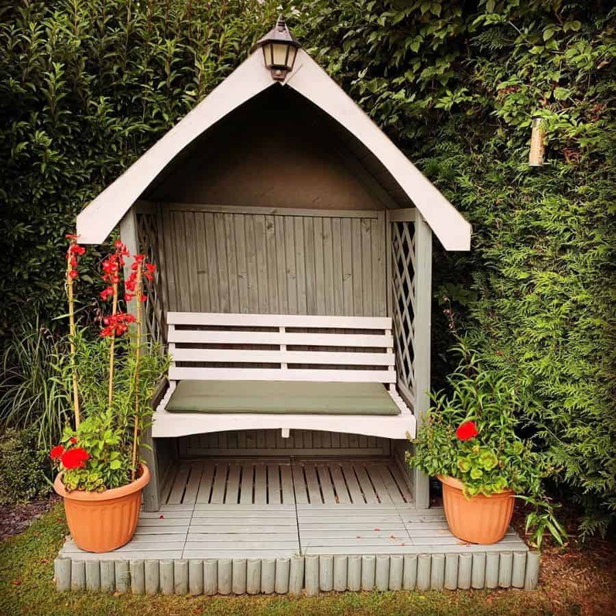small backyard wood gazebo with bench and terracotta pot plants