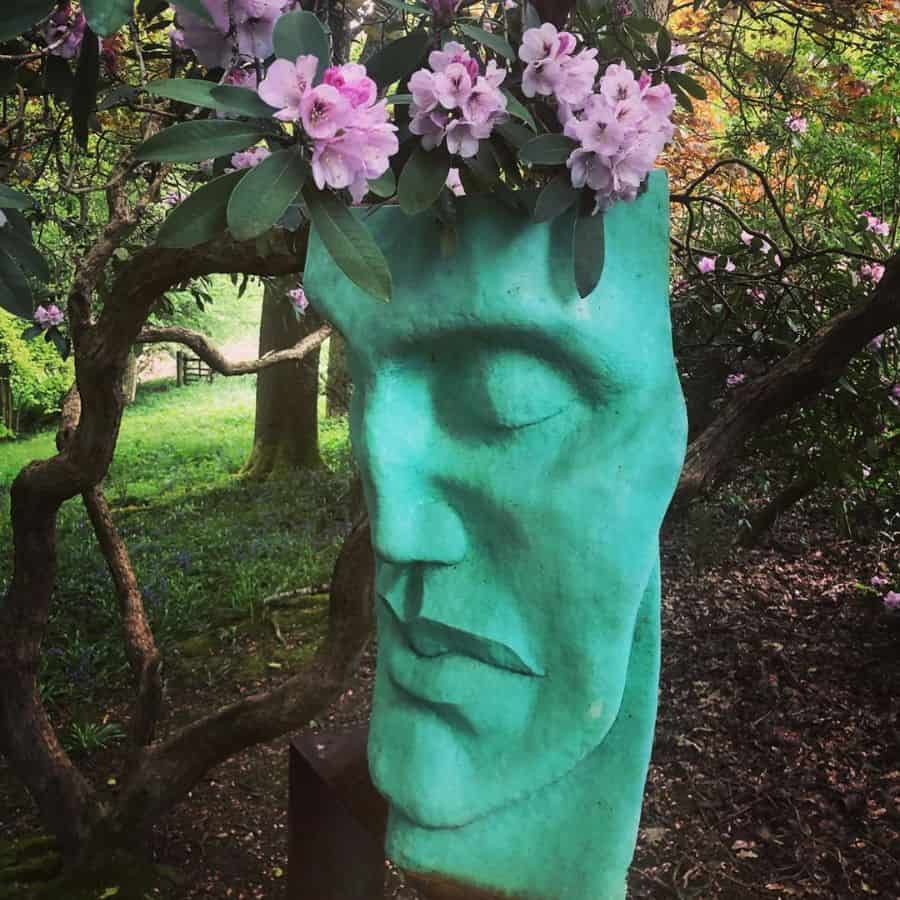 blue face garden statue with flowers on head