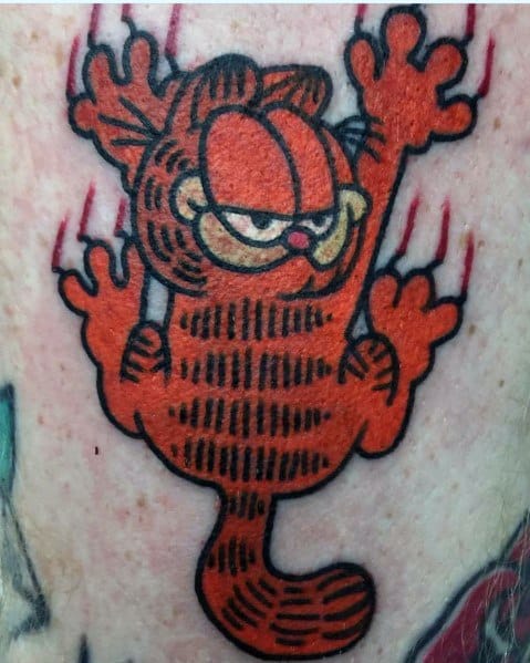 Bold Garfield tattoo with a mischievous look, clawing down with red scratch marks—classic and playful cartoon-style design.