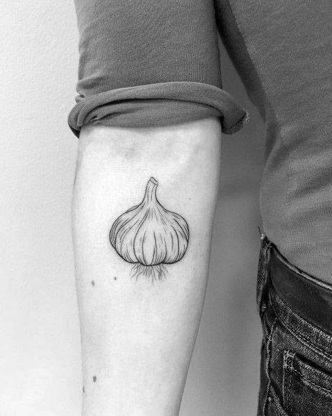 Minimalist garlic tattoo on the forearm with fine line details and subtle shading, creating a simple yet elegant botanical design.