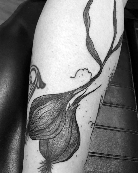 Black and grey garlic tattoo with delicate shading and flowing stems, creating an artistic and organic botanical design.