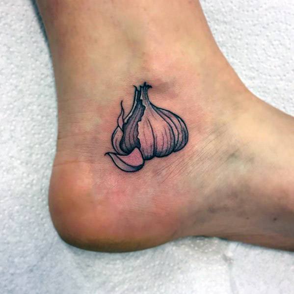 Fine-line garlic tattoo on the ankle with subtle shading and peeled cloves, creating a delicate and minimalist botanical design.