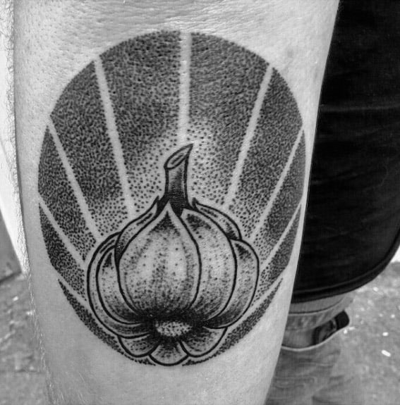 Bold blackwork garlic tattoo with intricate dotwork shading and a radiant background, creating a striking and graphic design.