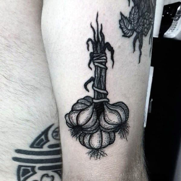 Bold black ink garlic tattoo with fine shading and detailed texture, featuring a tied stem for a rustic and organic botanical design.