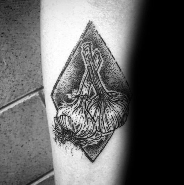 Black and grey garlic tattoo with fine dotwork shading and a geometric background, creating a bold and detailed botanical design.