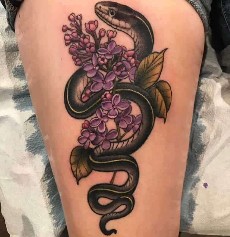 Bold tattoo of a black snake coiled around vibrant lilac flowers and green leaves, blending realism with neo-traditional shading.