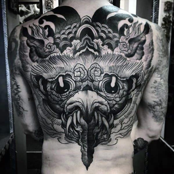 Dark Garuda tattoo covering the full back, featuring intense eyes, a hooked beak, and swirling cloud-like patterns in a bold blackwork style.