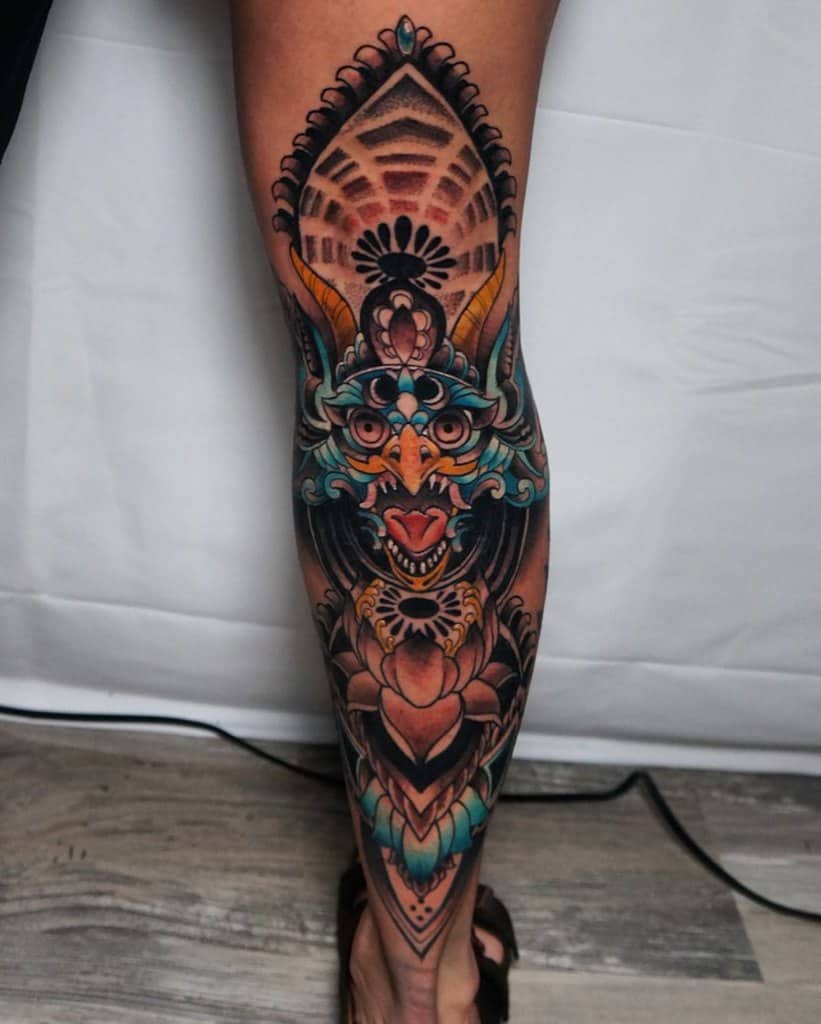 Vibrant tattoo leg sleeve featuring a colorful and intricate design of a demonic face with bold geometric patterns and floral elements
