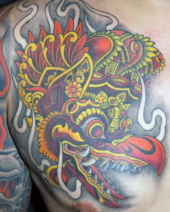 Vibrant Garuda tattoo on the chest featuring bold red, yellow, and orange patterns with intricate detailing and dynamic shading.