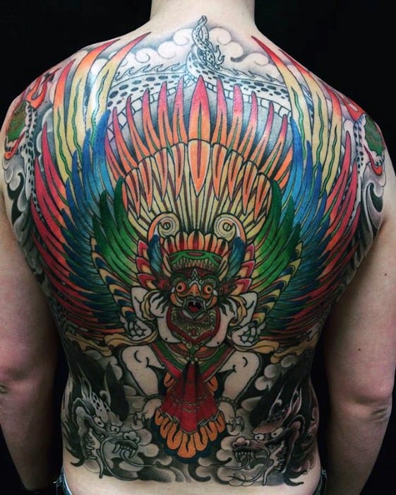 Full back Garuda tattoo featuring a vibrant, rainbow-colored wing span and fierce deity figure with bold outlines and smoky background elements.