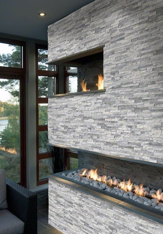 Modern stone wall with built-in gas fireplace and layered flames in a sleek, contemporary space.