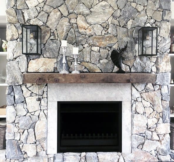 Gas fireplace with a black frame, rustic stone surround, and wooden mantle.