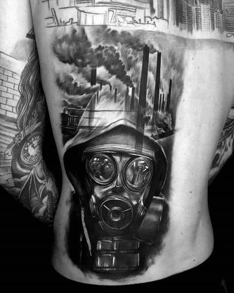 Black and grey back tattoo featuring a figure in a gas mask with an industrial landscape, smoking chimneys, and dark shading for a dystopian theme.