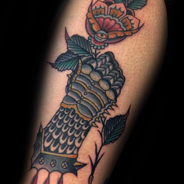 Colorful tattoo of a medieval gauntlet holding a blooming rose, with green leaves and gold, blue, and red detailing.