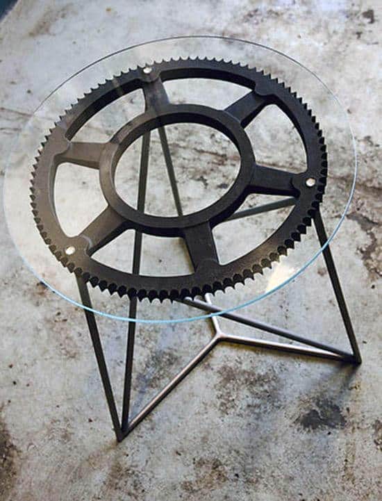 Glass table with a metal gear-shaped base on a concrete floor