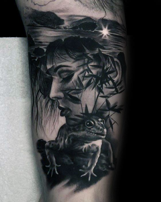 Black and grey tattoo of a woman’s face with bamboo silhouettes, a gecko on a rock, and a serene ocean sunset in the background.
