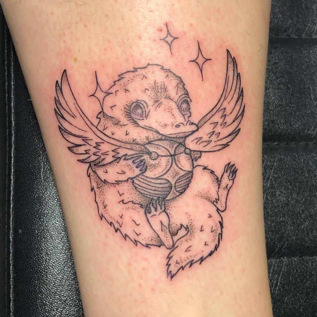Minimalist black ink tattoo of a Niffler holding a golden snitch with wings, surrounded by sparkles