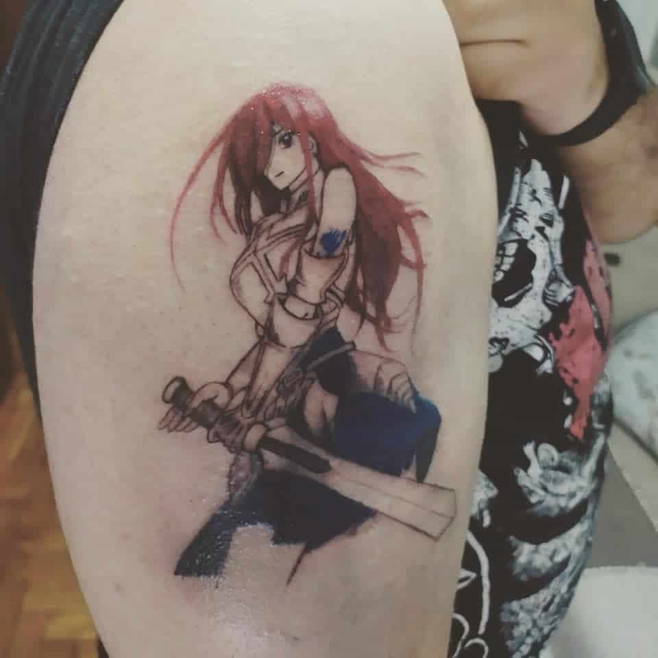 Colorful tattoo of Erza Scarlet from Fairy Tail on the upper arm, featuring flowing red hair, armor details, and her signature sword in a battle-ready pose.