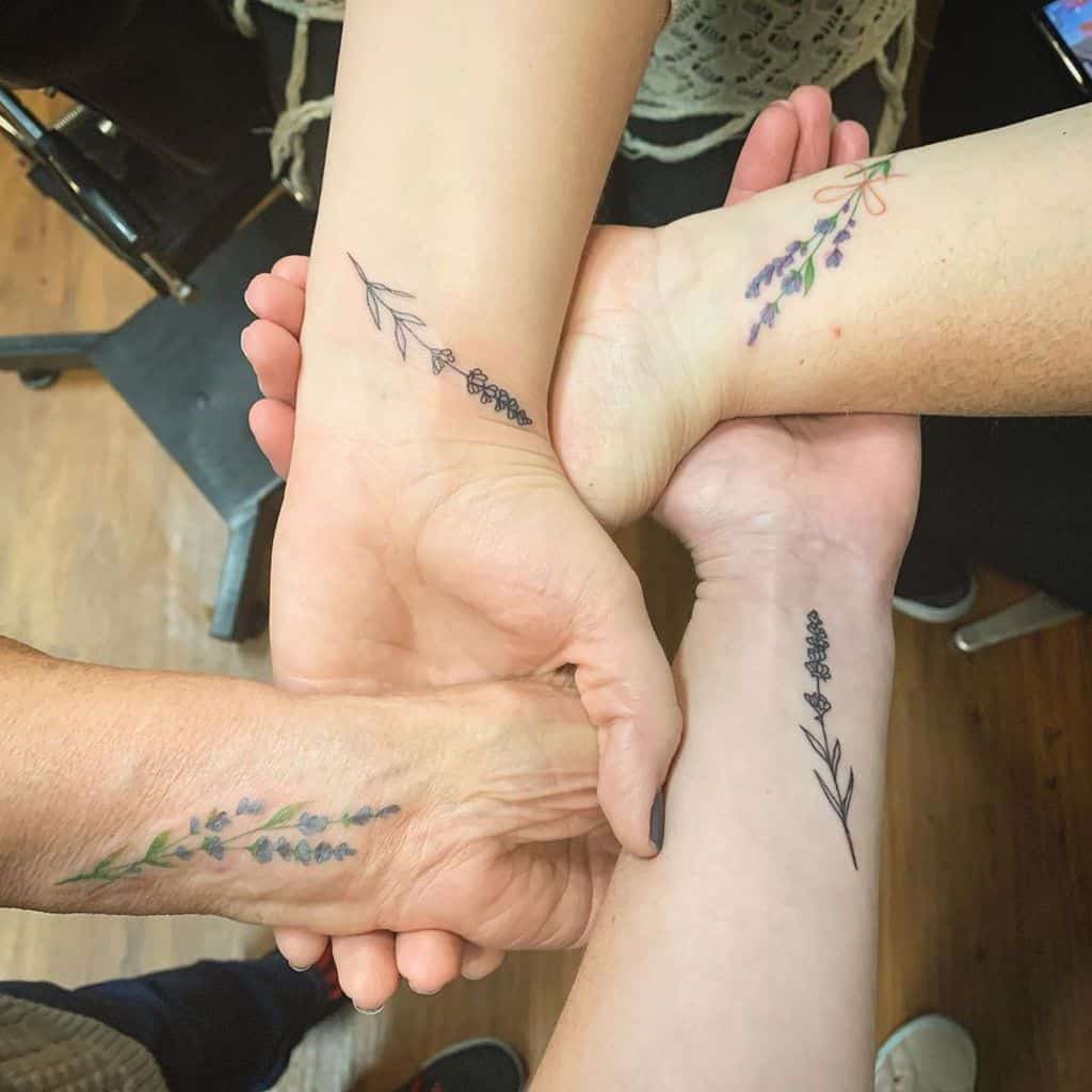 A group of four arms displaying matching lavender flower tattoos, with each arm showing a different variation of the design. The tattoos are colorful and delicate, placed along the forearms.