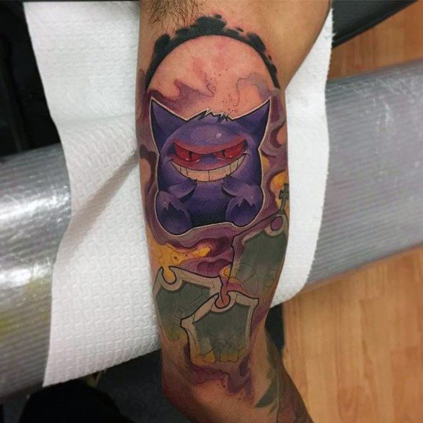 Gengar tattoo with eerie red eyes emerging from swirling smoke, set above haunted graveyard elements in a dark, mystical design.