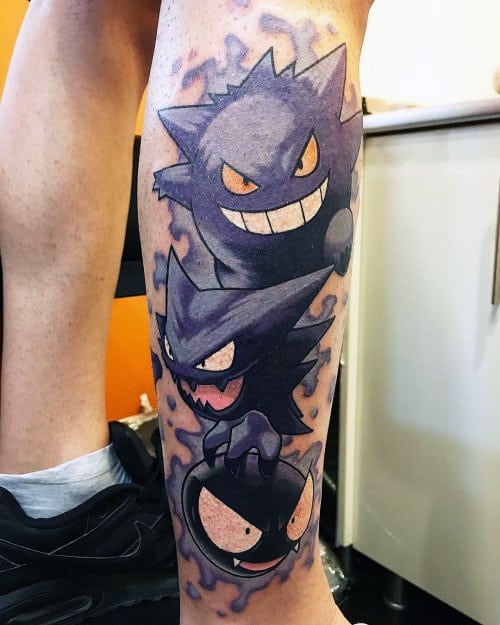 Vibrant leg tattoo of Gastly, Haunter, and Gengar stacked in evolution order, surrounded by a swirling purple aura and bold outlines.
