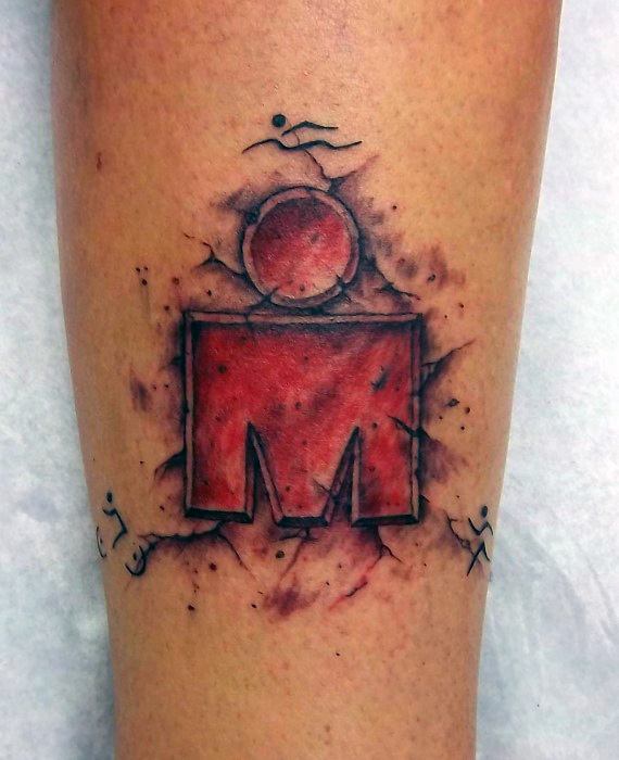 Ironman logo tattoo with red and black ink, surrounded by splattered effects and small swimmer, biker, and runner icons.