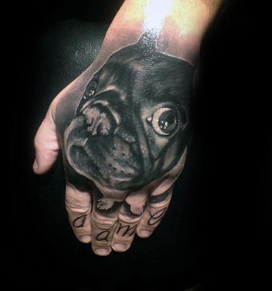 Realistic tattoo of a dog's face on the back of a hand, with a word tattooed across the fingers