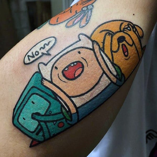 Adventure Time tattoo of Finn, Jake, and BMO squeezed together with Finn saying "No~", inked on the inner arm.