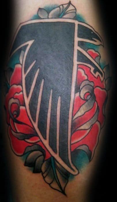 Atlanta Falcons logo tattoo in bold black, layered over vibrant red roses with green and blue shading for a striking contrast.