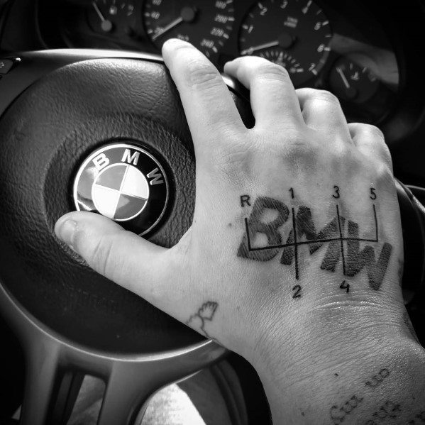 Bold BMW gear shift tattoo on hand, featuring a stylized BMW logo integrated with a manual transmission pattern for a dynamic design.
