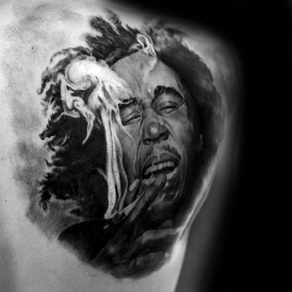 Black and gray tattoo of Bob Marley with expressive emotion, eyes shut and smoke rising from a joint, capturing a raw and soulful moment.