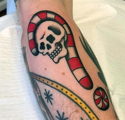 Bold candy cane tattoo with a skull design, blending festive and edgy elements in a striking traditional tattoo style.