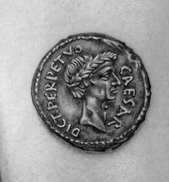 Realistic tattoo of an ancient Roman coin featuring Julius Caesar, with intricate shading and a worn, antique look for historical appeal.