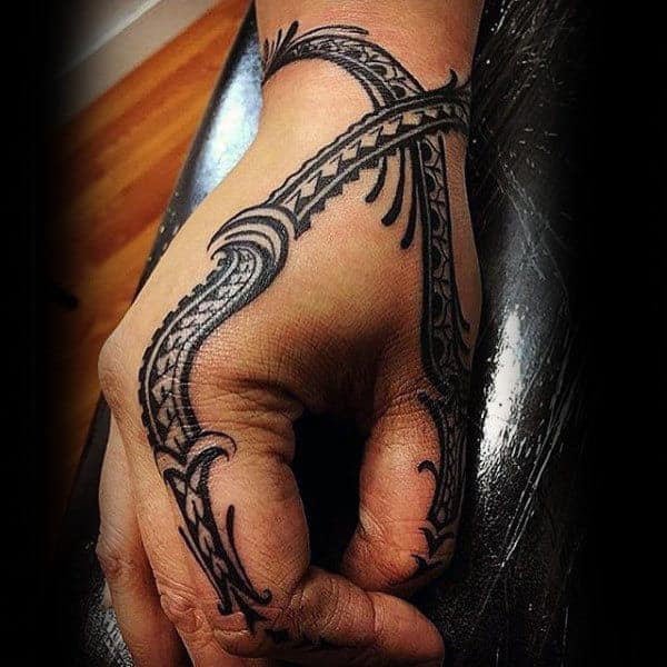 Hand with intricate black tribal tattoo covering the back and extending to the fingers
