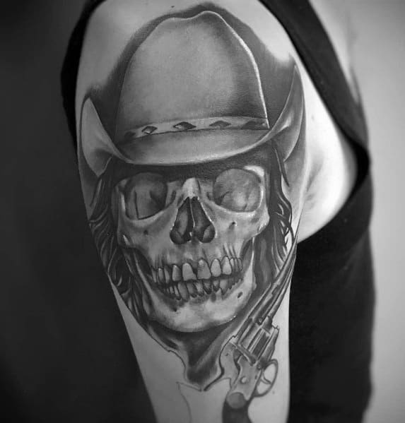 Realistic black and gray tattoo of a cowboy skull wearing a hat, with long hair and a revolver, creating a detailed and intense Western design.