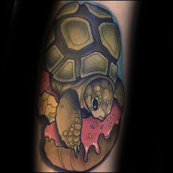 Tattoo of a realistic turtle sitting inside a bitten pink frosted donut, combining nature with a fun food-themed twist.