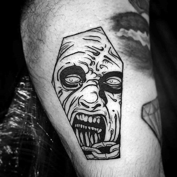 Blackwork Evil Dead tattoo of a screaming deadite face framed in a coffin shape with bold lines and eerie expression.