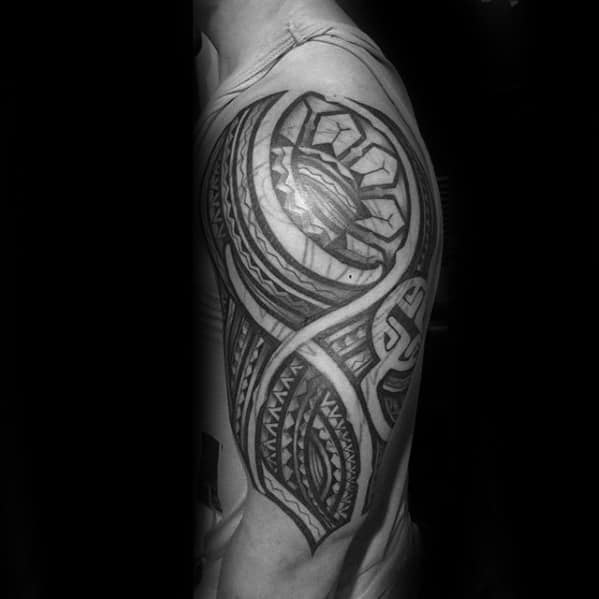 Filipino sun tattoo on the upper arm with stylized rays, tribal wave patterns, and textured geometric details in a flowing half-sleeve design.