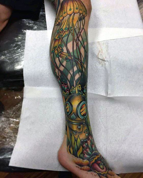 Full-leg underwater tattoo featuring a deep-sea diver helmet, vibrant jellyfish, and colorful marine creatures in a surreal style.