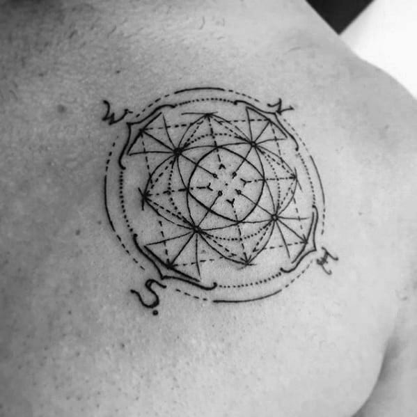 Abstract geometric compass tattoo on upper chest with intricate dot work, lines, and directional letters for a symbolic design.