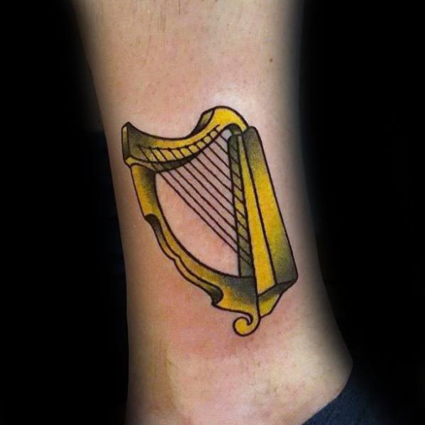 Gentleman With Gold Harp Tattoo On Lower Leg